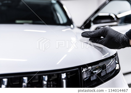 Ceramic coating application on white car hood and front panel during professional car detailing 134014467