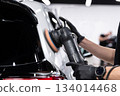 Ceramic coating application on black car rear body panel during professional car detailing 134014468
