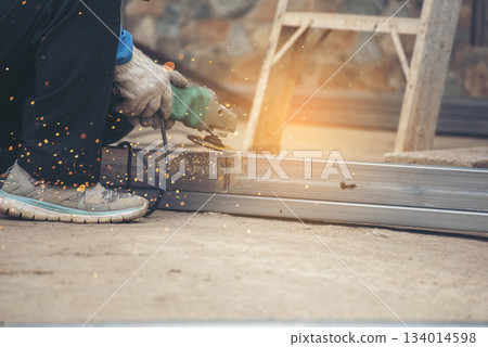 Construction Worker hands using Welding machinery iron metal sparking. Men hands wear protective glove Hot flame metal work cutting fire iron workshop. Locksmith use Welding machine cut metal process Construction Worker hands using Welding machinery iron metal sparking. Men hands wear protective glove Hot flame metal work cutting fire iron workshop. Locksmith use Welding machine cut metal process 134014598