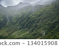 Green mountain walls with streaming waterfalls during cloudy and rainy day, Austrian Alps 134015908