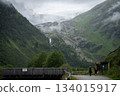 Hikers couple walking the alpine valley towards massive glacier ahead of them, Austrian Alps 134015917