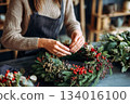 Creating a beautiful holiday wreath with natural materials in a cozy workshop decorated for the festive season 134016100