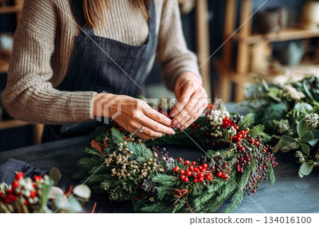 Creating a beautiful holiday wreath with natural materials in a cozy workshop decorated for the festive season Creating a beautiful holiday wreath with natural materials in a cozy workshop decorated for the festive season 134016100