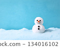 Cute snowman with a cheerful smile stands on soft snow against a bright blue background during winter 134016102