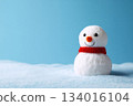 Colorful snowman sitting cheerfully in a snow-covered landscape against a bright blue background during a winter day 134016104