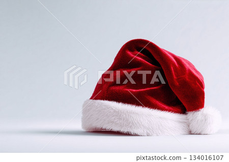 Classic red Santa hat resting on a plain background, evoking holiday spirit and festive celebrations during the winter season 134016107
