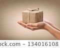 Present wrapped in burlap held gently in two hands, symbolizing the spirit of giving during special occasions and celebrations 134016108