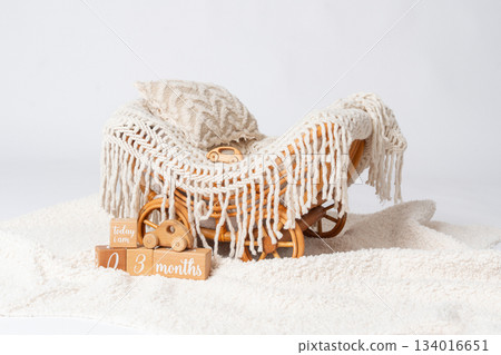 Soft nursery decor arrangement with knitted blanket, textured pillow and wooden toy sleigh on a fluffy surface. Warm neutral tones create a calm atmosphere suited for baby room styling, interior Soft nursery decor arrangement with knitted blanket, textured pillow and wooden toy sleigh on a fluffy surface. Warm neutral tones create a calm atmosphere suited for baby room styling, interior 134016651