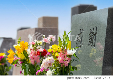 一塊刻有「感恩」二字的西式墓碑,旁邊擺放著色彩鮮豔的佛教花卉。 一塊刻有「感恩」二字的西式墓碑,旁邊擺放著色彩鮮豔的佛教花卉。 134017403