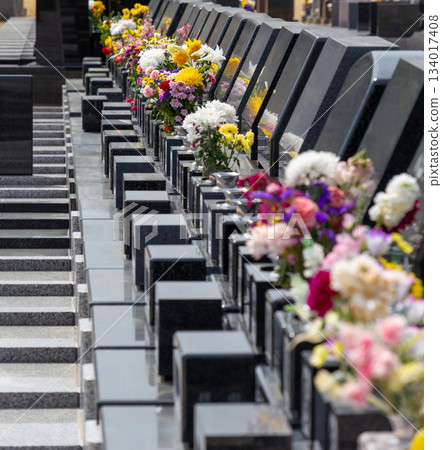 A scene of rows of gravestones in a Japanese cemetery. Many colorful Buddhist flowers are offered. A scene of rows of gravestones in a Japanese cemetery. Many colorful Buddhist flowers are offered. 134017408