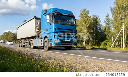 Semi-truck with a fully loaded cargo trailer driving along countryside road. Transport, cargo delivery concept Semi-truck with a fully loaded cargo trailer driving along countryside road. Transport, cargo delivery concept 134017659