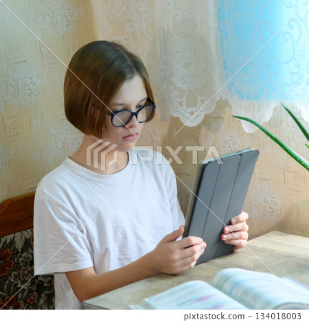 student in glasses uses a tablet for distance learning 134018003
