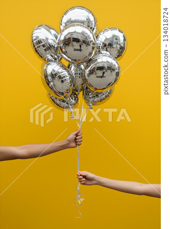 Silver Foil Balloons Against Yellow Background 134018724