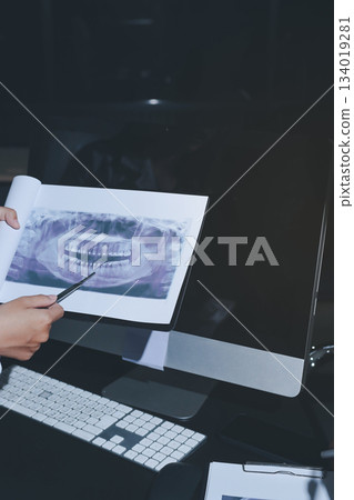 Two doctors and a female nurse meet at a table in the hospital, collaborating on medical tasks using laptops and computers 134019281