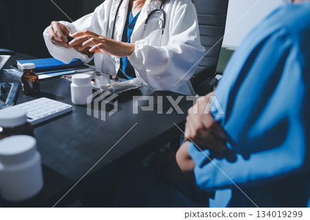Female doctor holding a medicine bottle is checking the quality of medicine for any side effects the patient or not and recording patient information at the hospital. medical and health care concept Female doctor holding a medicine bottle is checking the quality of medicine for any side effects the patient or not and recording patient information at the hospital. medical and health care concept 134019299