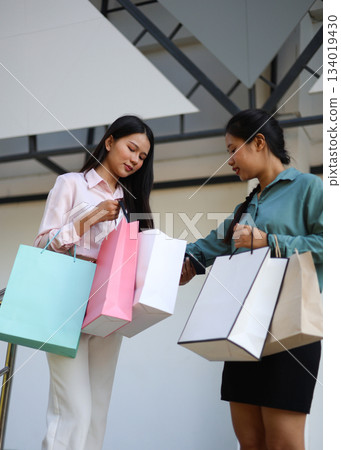 Two female friends happily shopping together at a mall. Two female friends happily shopping together at a mall. 134019430