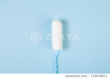 Hygienic cotton tampon on blue background. Feminine menstrual hygiene products. Womens health concept. Copy space. Hygienic cotton tampon on blue background. Feminine menstrual hygiene products. Womens health concept. Copy space. 134019621