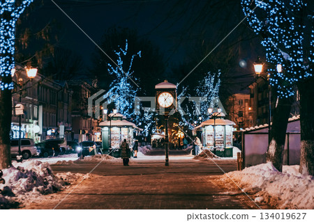 Antique clock in city square. Christmas festive decorations on street. Antique clock in city square. Christmas festive decorations on street. 134019627