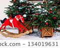 Christmas decorations on porch of house. Festive tree with red Christmas balls and wooden red horse. Holiday season, street decor. 134019631
