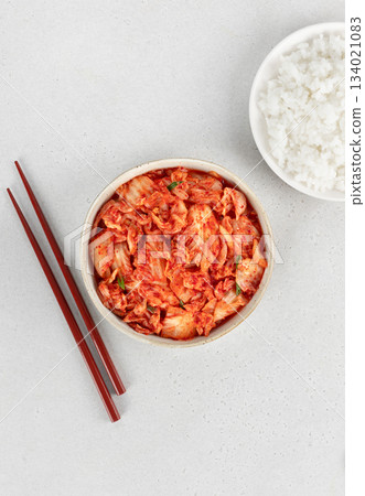 Korean fermented cabbage kimchi in bowl with steamed rice and wooden chopsticks on a white background. Probiotic food. Korean fermented cabbage kimchi in bowl with steamed rice and wooden chopsticks on a white background. Probiotic food. 134021083
