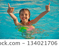 Portrait of laughing girl of 9 years in swimming pool gesturing super, fine 134021706