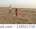 Father and daughter playing badminton on beach 134021716