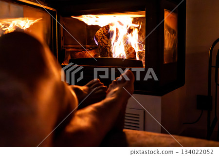 Woman's feet in front of the fireplace. Woman warms herself by the fire Woman's feet in front of the fireplace. Woman warms herself by the fire 134022052