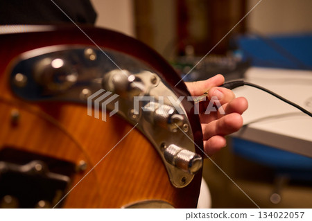 Musician setting up equipment, Preparing bass guitar for recording, Electric bass player organizing gear in studio, Closeup of musician tuning and adjusting bass instrument Musician setting up equipment, Preparing bass guitar for recording, Electric bass player organizing gear in studio, Closeup of musician tuning and adjusting bass instrument 134022057