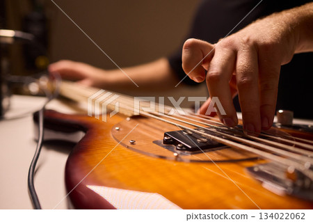 Musician setting up equipment, Preparing bass guitar for recording, Electric bass player organizing gear in studio, Closeup of musician tuning and adjusting bass instrument Musician setting up equipment, Preparing bass guitar for recording, Electric bass player organizing gear in studio, Closeup of musician tuning and adjusting bass instrument 134022062
