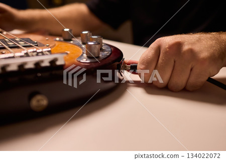 Musician setting up equipment, Preparing bass guitar for recording, Electric bass player organizing gear in studio, Closeup of musician tuning and adjusting bass instrument Musician setting up equipment, Preparing bass guitar for recording, Electric bass player organizing gear in studio, Closeup of musician tuning and adjusting bass instrument 134022072