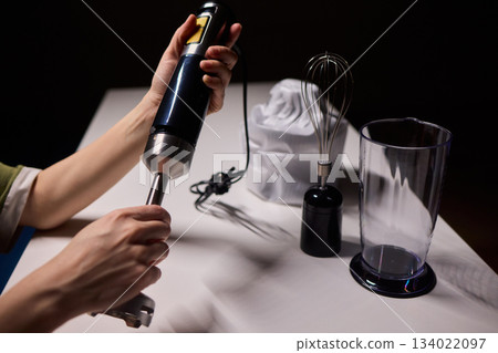 Preparing blender on kitchen counter, Scene shows detailed process of assembling immersion blender, Cozy kitchen scene of hands carefully putting together blending device Preparing blender on kitchen counter, Scene shows detailed process of assembling immersion blender, Cozy kitchen scene of hands carefully putting together blending device 134022097