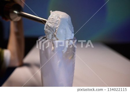 Creamy scoop presentation, Barista serving frosty ice cream, Frothy milkshake with chilled condensation display, Indulgent treat being carefully plated in minimalist setting 134022115