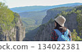 Rear view, a woman traveling through the mountains of Turkey with a backpack on the edge of the Tazi Canyon admiring the mountains, a girl outdoors enjoying the view of the Tazi Canyon. 134022381