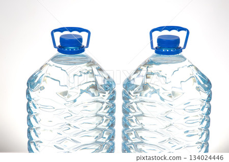 Two transparent water bottles with blue caps and a textured pattern, 134024446