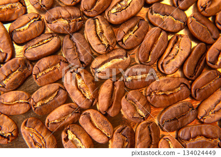 Detailed shot of roasted coffee beans with natural splits, arranged on a golden tray 134024449