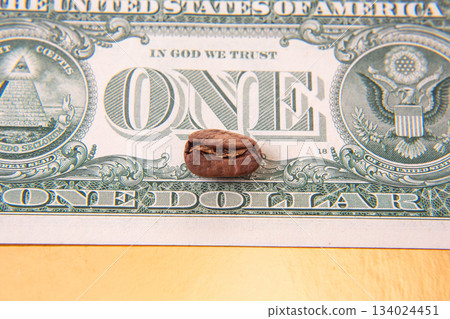 Close-up of a cracked coffee bean resting on a U.S. one-dollar bill 134024451