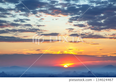 Ethereal sky filled with heavy clouds and golden light rays breaking through at sunset 134024467