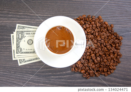 cup of coffee with fresh beans and a touch of cash on a wooden table. coffee business 134024471