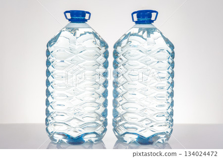Two transparent water bottles with blue caps and a textured pattern 134024472