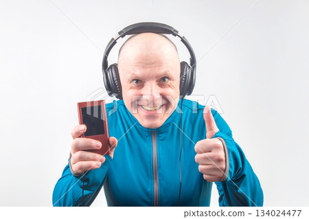 happy man in portable full-size headphones listens to music using a digital player. 134024477
