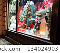 Festive shop window display decorated Christmas tree with lights and ornaments. Gifts in colorful wrapping are arranged below 134024903