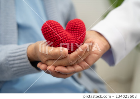 Doctor giving a red heart to senior patient in hospital. Doctor giving a red heart to senior patient in hospital. 134025608