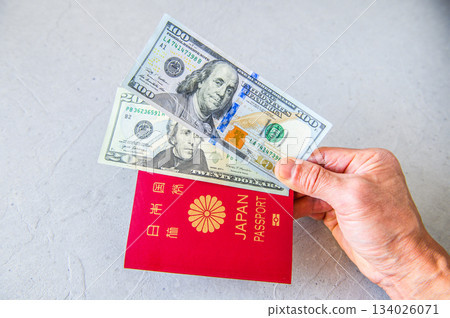 Hold the US 100 and 20 dollar bills and your Japanese passport with your right hand, from the right side. Hold the US 100 and 20 dollar bills and your Japanese passport with your right hand, from the right side. 134026071