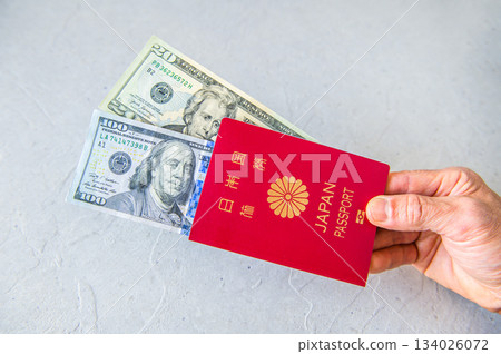 2. 右手從右側出示100美元和20美元的美國鈔票以及日本護照 134026072