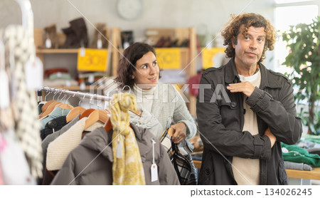 Annoyed man standing next to woman in store Annoyed man standing next to woman in store 134026245