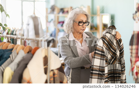 Family clothing store, senior woman customer choose plaid coat 134026246