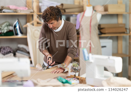 Man tailor cuts paper dress pattern and work with hand snip Man tailor cuts paper dress pattern and work with hand snip 134026247