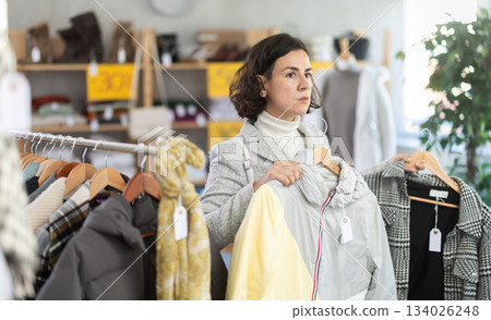 woman chooses outerwear at a sale in a showroom woman chooses outerwear at a sale in a showroom 134026248