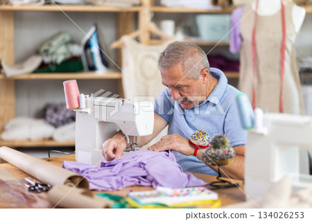 Mature man tailor sewing in workshop Mature man tailor sewing in workshop 134026253