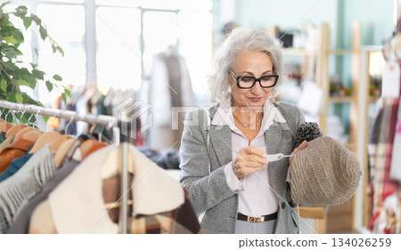 Family clothing store, senior woman customer choose winter head cover 134026259